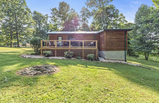 back view of home, back deck, back yard, log cabin, metal roof, yard, landscaping, trees