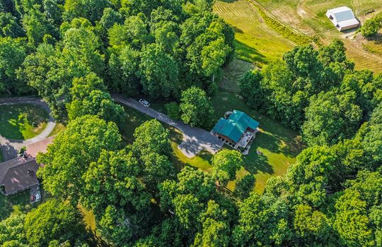 Aerial view of rental property, metal roof, yard, trees