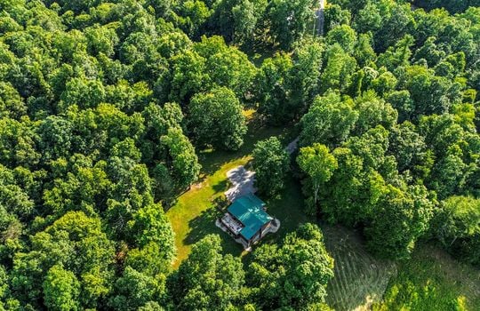 Aerial view of rental property, metal roof, yard, trees