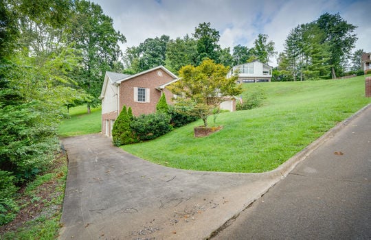 View from secondary driveway, one story, brick home, two door drive under garage, concrete driveway, front yard, landscaping