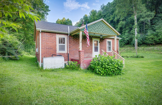 left side exterior view, brick exterior, covered front porch, stairs, front door, cottage, front yard, landscaping, trees