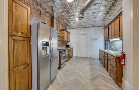 kitchen, refrigerator, oven/range, exposed brick wall, cabinets, countertops