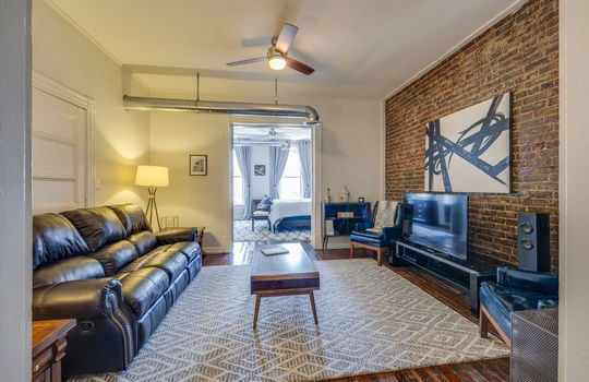 living room/den, hardwood flooring, exposed brick wall, ceiling fan