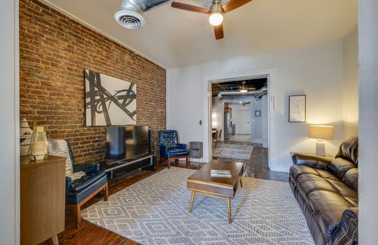 living room/den, exposed brick wall, ceiling fan, hardwood flooring