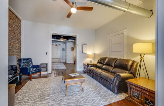 living room/den, exposed brick wall, ceiling fan, hardwood flooring