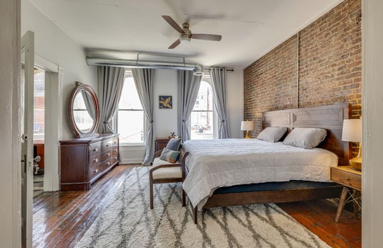 bedroom, windows, ceiling fan, hardwood flooring, exposed brick wall