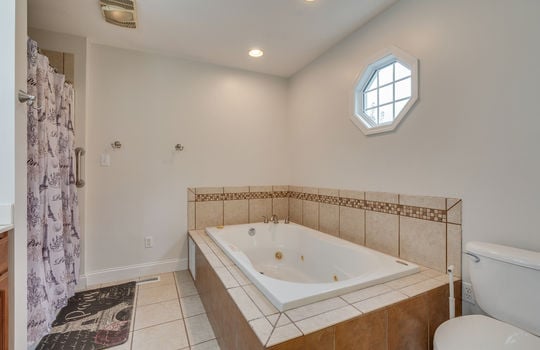 garden/soaking tub, primary bathroom, shower, toilet, tile flooring, window