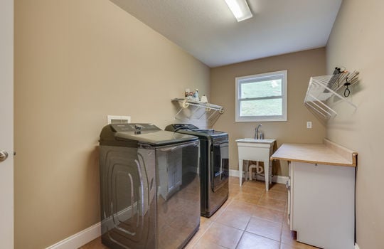 laundry area, tile flooring, utility sink, shelving, lower cabinet with countertop