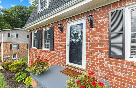 front door, storm door, front steps, brick exterior, dutch colonial home