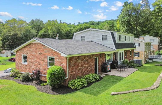 back side view of property, brick, dutch colonial home, back yard, retaining wall, patio, landscaping