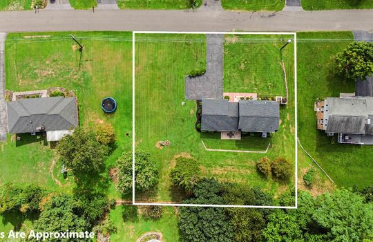 aerial view of property, roof, driveway, yard, back yard, front yard, road, trees