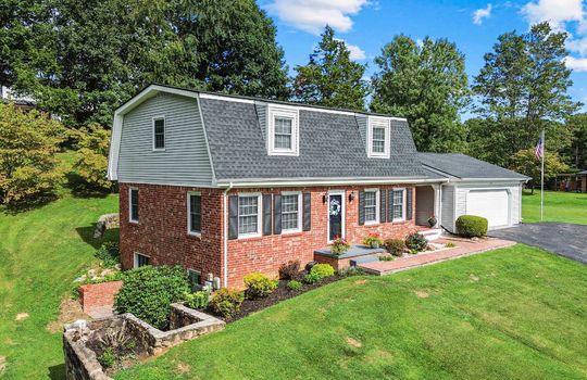 brick dutch colonial home, front yard, garage, driveway, trees