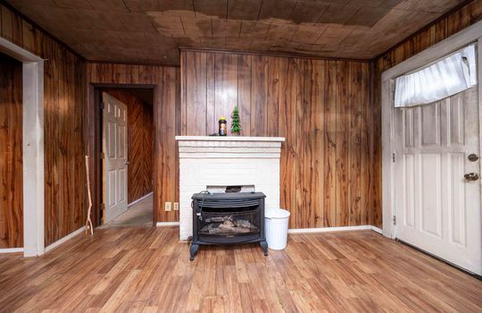 front door, living room, window, laminate flooring, paneling walls, brick fireplace