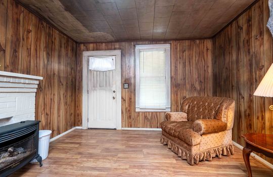 front door, living room, window, laminate flooring, paneling walls, brick fireplace