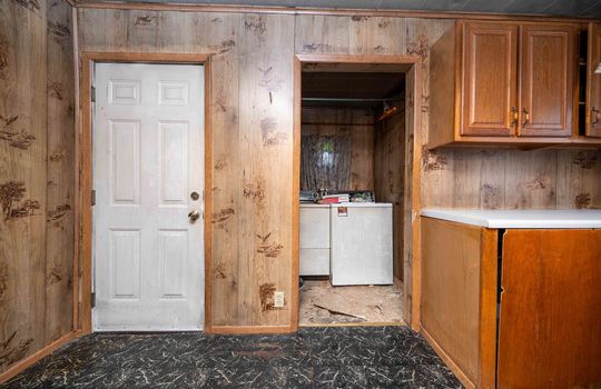 kitchen, cabinets, laminate flooring, exterior door, paneling walls, cabinets, countertops, laundry area