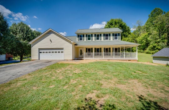 front yard, traditional home, two levels, wrap around porch, covered porch, garage, garage door, windows, vinyl siding, driveway