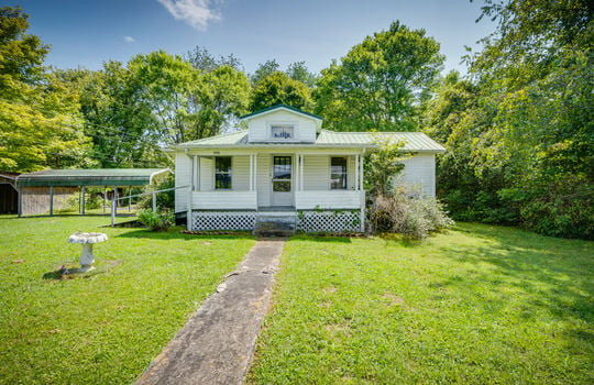 cottage, one level, vinyl siding, front porch, front door, steps, sidewalk, front yard, carport, trees, metal roofing