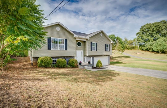 split foyer, vinyl siding, front door, front yard, driveway, garage door, windows, trees, landscaping