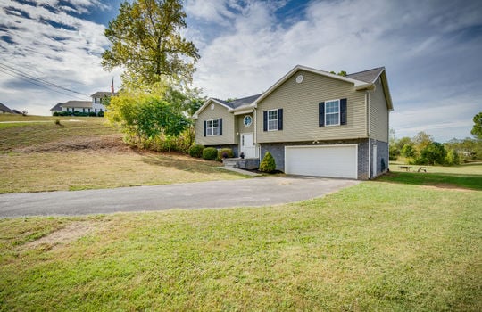 split foyer, vinyl siding, front door, front yard, driveway, garage door, windows, trees, landscaping