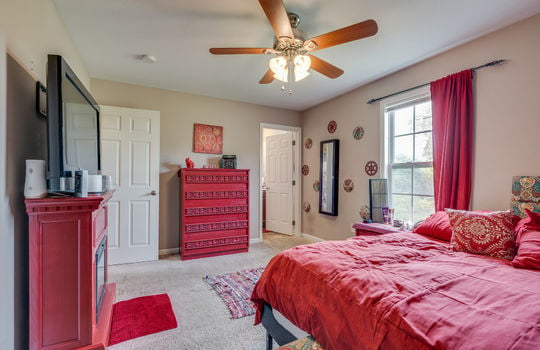 primary bedroom, carpet, ceiling fan, door to primary bathroom, window