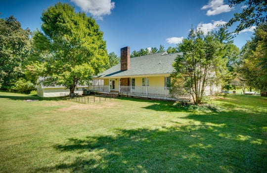 back of home, two story traditional home, wrap around porch, vinyl siding, trees, back yard