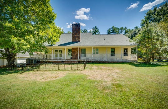 back of home, two story traditional home, wrap around porch, vinyl siding, trees, back yard