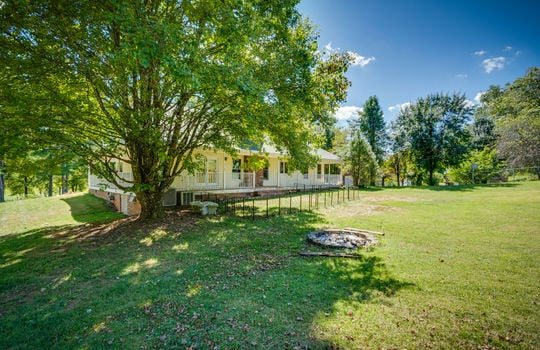 back of home, two story traditional home, wrap around porch, vinyl siding, trees, back yard