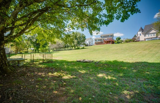 back of home, two story traditional home, wrap around porch, vinyl siding, trees, back yard