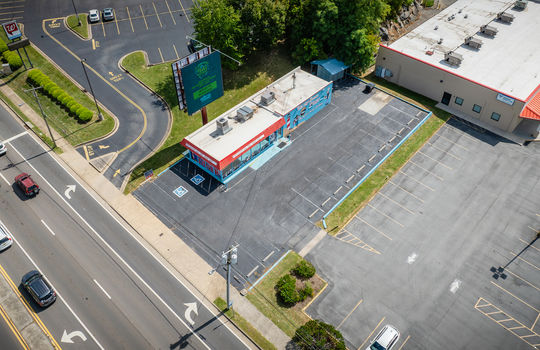 aerial view of restaurant, parking spaces, roof, billboard, sidewalk