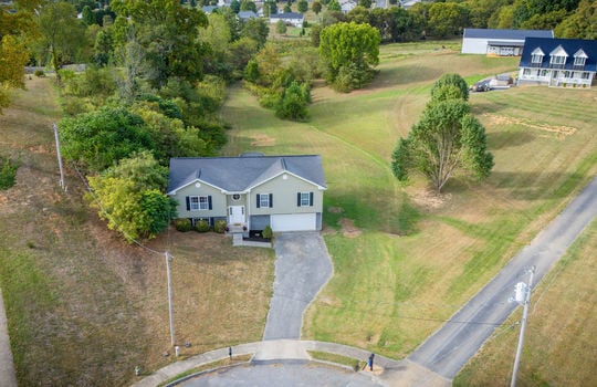 aerial view of home, front yard, driveway, split level home, garage, vinyl siding, roof, trees, landscaping, sidewalk