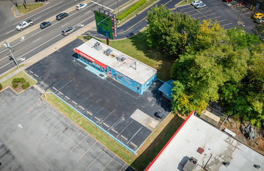 aerial view of restaurant, parking spaces, roof, billboard, sidewalk