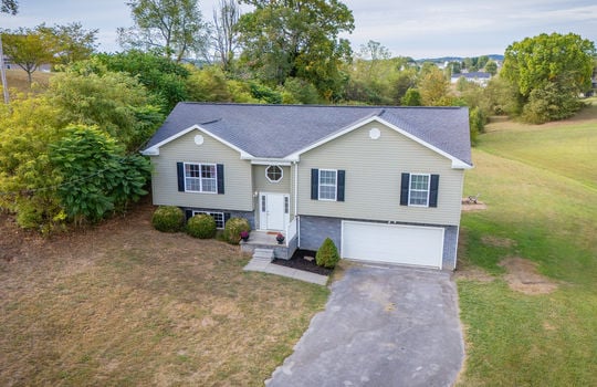 aerial view of home, front yard, driveway, split level home, garage, vinyl siding, roof, trees, landscaping, sidewalk