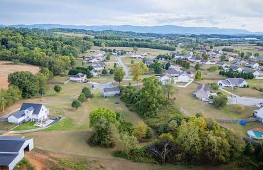 aerial view from back of property, back yard, trees, split level home, neighboring homes, neighborhood, mountains