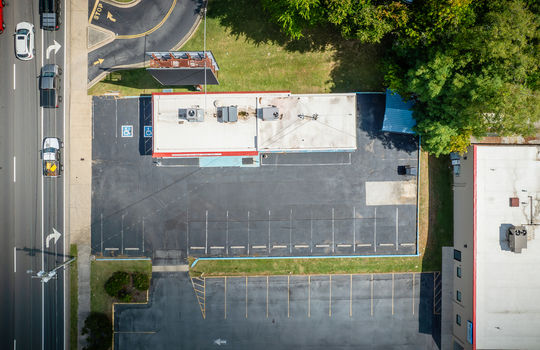 aerial view of restaurant, parking spaces, roof, billboard, sidewalk