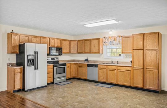 kitchen, refrigerator, oven/range, built-in microwave, dishwasher, sink, cabinets, countertops, vinyl flooring, window above sink