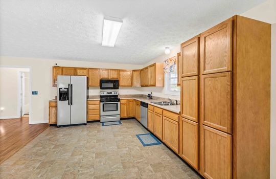 kitchen, refrigerator, oven/range, built-in microwave, dishwasher, sink, cabinets, countertops, vinyl flooring, window above sink