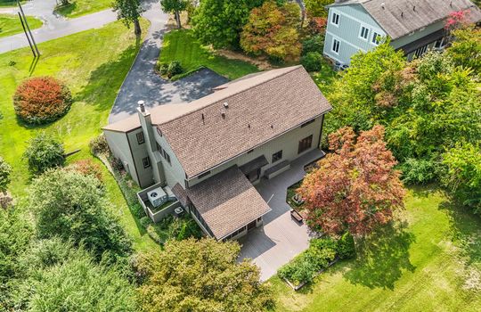 back aerial view of home, 2 story contemporary home, trees, back deck, sunroom, roof, front yard, driveway, road