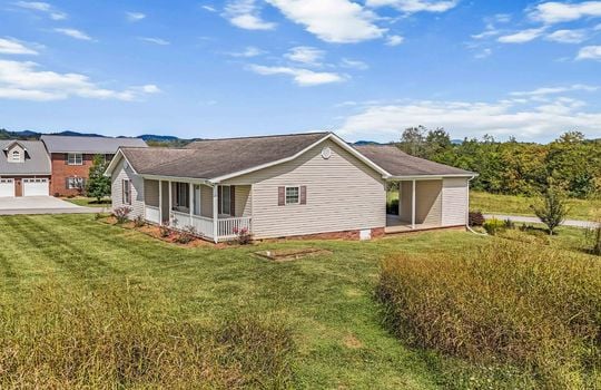 side view of home, ranch style home, vinyl siding, covered front porch, carport, roof, yard, landscaping