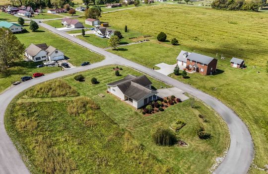 aerial view of home from back of property, yard, driveway, road, neighboring homes