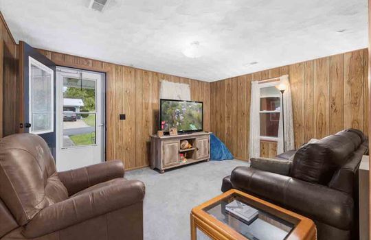 living room, paneling walls, carpet, windows, front door