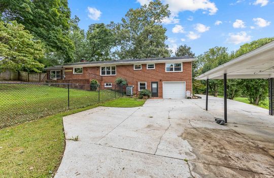 back view of home, concrete driveway, garage door, brick ranch, back yard