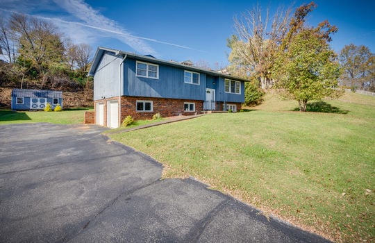 split foyer, driveway, two car garage, landscaping, front door, trees