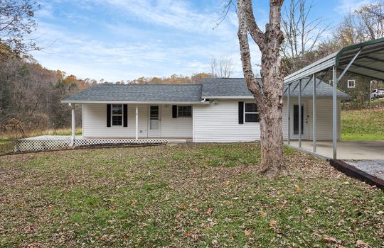 front yard, gravel driveway, carport, house, vinyl siding, covered front porch, mountain views