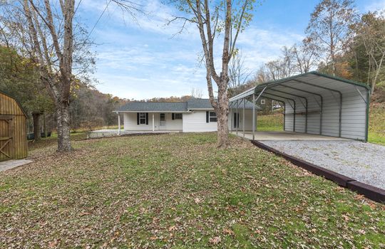 front yard, gravel driveway, carport, house, vinyl siding, covered front porch, mountain views