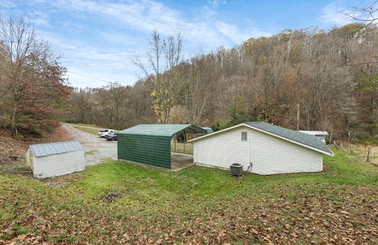 side view of home, covered carport, gravel driveway, yard, storage shed