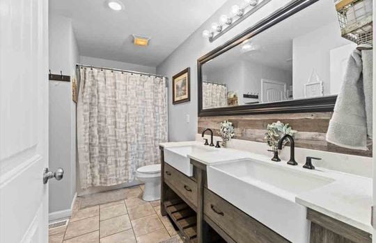 primary bathroom, double vanity sinks, tile flooring, toilet, shower/tub