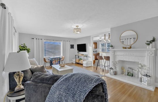 living room, window, hardwood flooring, entry to kitchen space, bar seating, fireplace