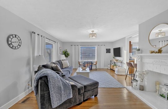 living room or reception area, hardwood flooring, fireplace, windows, bar seating