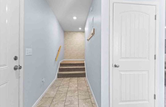 hallway to upper level stairs, closet, tile flooring, carpeted stairs