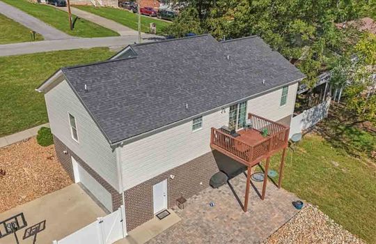 aerial view of back of home, back deck, drive under garage, patio, back yard, roof